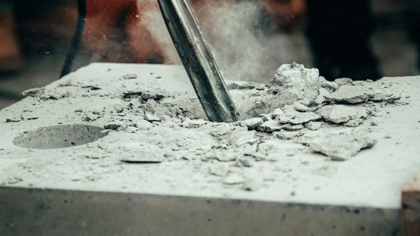 A detailed close-up of a power tool chipping away at a concrete block, capturing action and dust.
